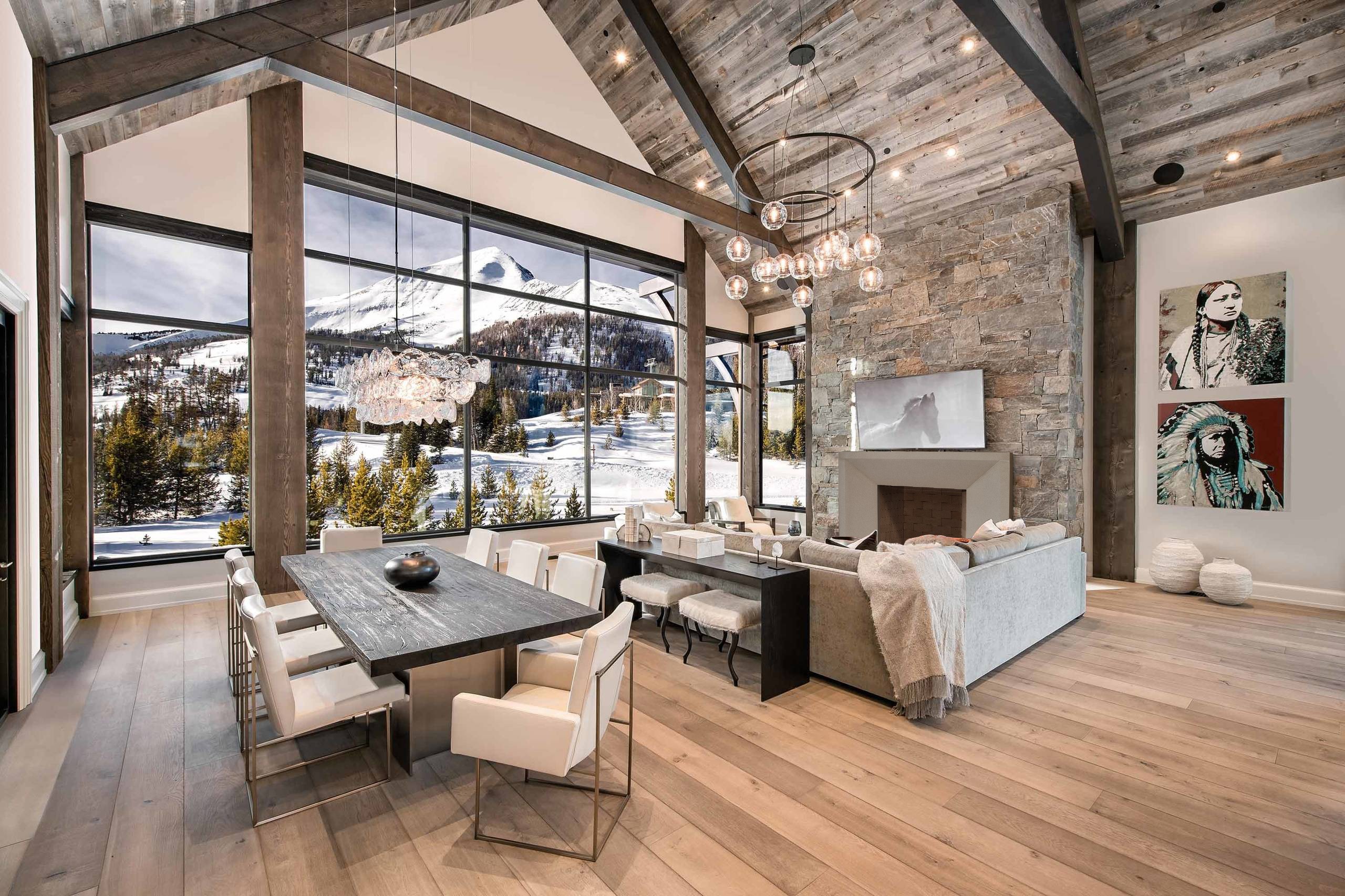 A large living room with wood beams, a mantel and a view of the mountains.